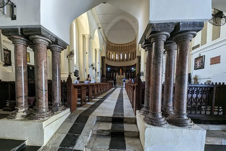 Innenansicht einer Kirche mit Marmorsäulen und Holzbänken.