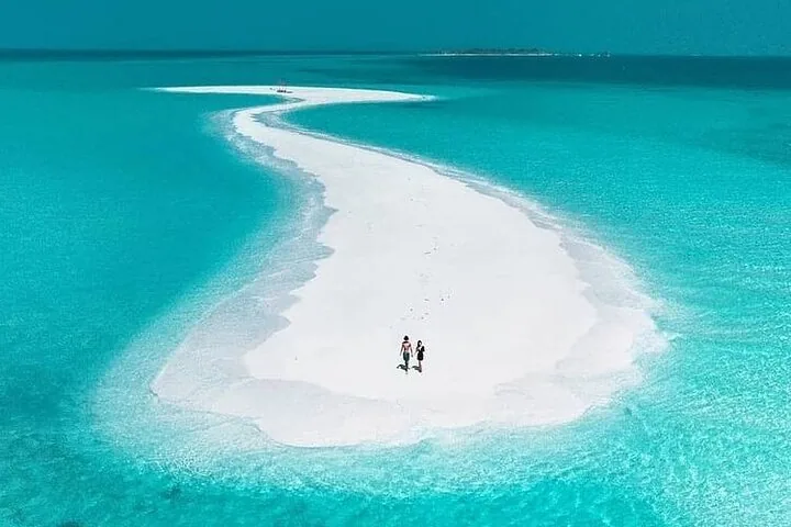 Luftaufnahme einer von türkisfarbenem Wasser umgebenen Sandbank, auf der zwei Personen spazieren.